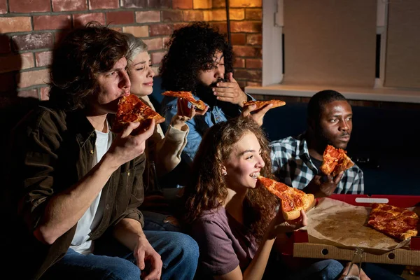 Přátelství, lidé, zábava a junk food koncept - šťastní přátelé jíst pizzu a sledování filmů nebo televizních seriálů doma — Stock fotografie