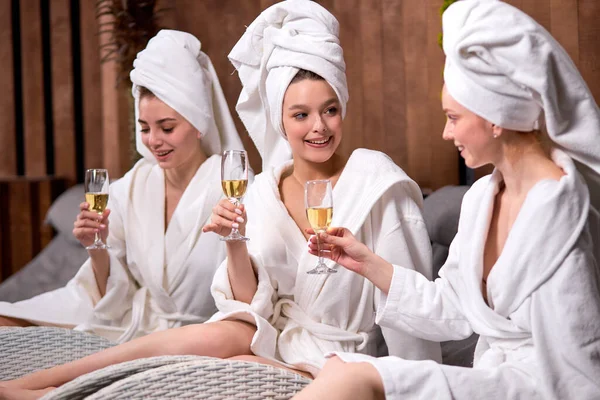 Women in bath towels communicating in spa salon while drinking champagne — Stock Photo, Image