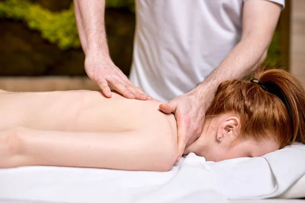 Redhead lady lying on stomach at spa, getting massage on neck and back — Stock Photo, Image