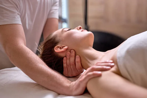 Young female at spa resort, receiving massage on neck and shoulders muscles — Stock Photo, Image