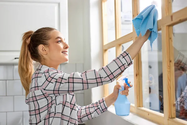 Vidro de janela de limpeza feminino com pano azul. Vista lateral. Limpeza de primavera, conceito de trabalho doméstico — Fotografia de Stock