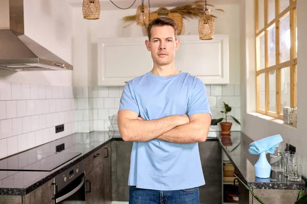 Портрет впевненого чоловіка, що стоїть на кухні позує на камеру зі складеними руками — стокове фото
