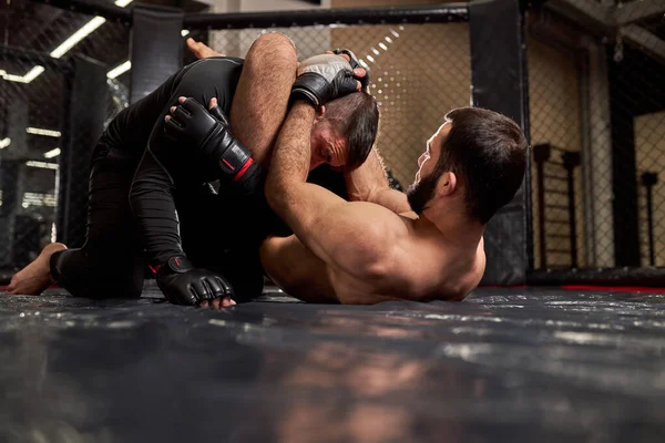 Los boxeadores luchan sin reglas en el octágono del ring. luchador sin camisa hace estrangulamiento recepción — Foto de Stock
