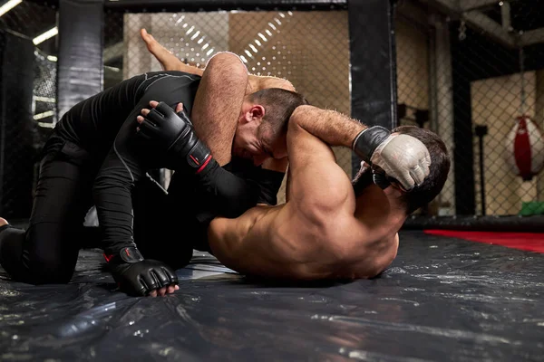 Wrestlers fighters fight without rules in the ring octagon. shirtless fighter makes strangling reception — Stock fotografie