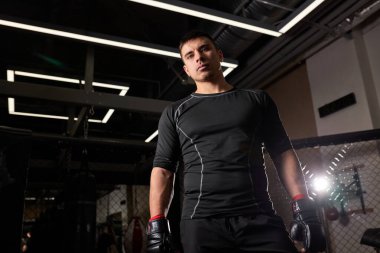 Eldivenli genç boksör dövüşten sonra ayakta duruyor. Antrenman sırasında genç boksör