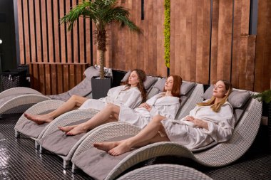 Spa sonrası dinlenen, bornozlu rahat kadınlara yan bakış.