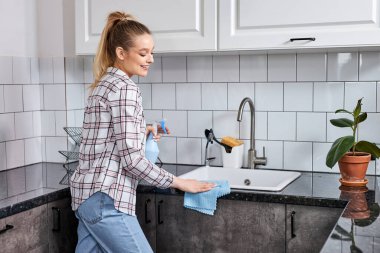 Genç bir kadın mutfak takımını bez ya da bezle yıkıyor. Profesyonel ev temizleme servisi.