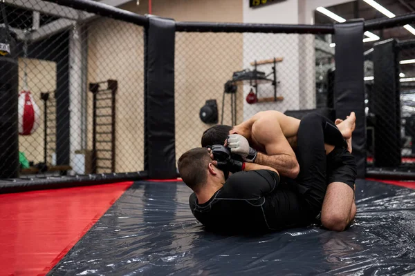 Jóvenes y poderosos luchadores de MMA luchan en el anillo de piso preparándose para la competencia en artes marciales —  Fotos de Stock