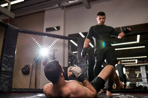 Mixed martial artist man in black wear win, stand over the losing fighter, winning — Zdjęcie stockowe