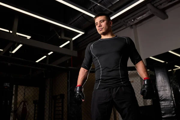 Confiante forte boxeador masculino em luvas de boxe está em pose pronta para lutar no ringue — Fotografia de Stock