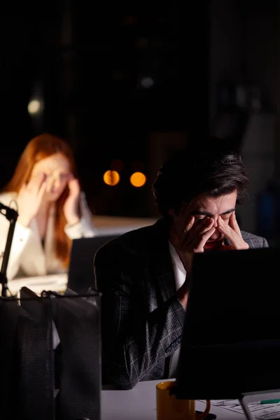 Ύπνος εξουθενωμένος νεαρός καυκάσιος άνδρας που εργάζεται αργά το βράδυ στο γραφείο με το PC — Φωτογραφία Αρχείου