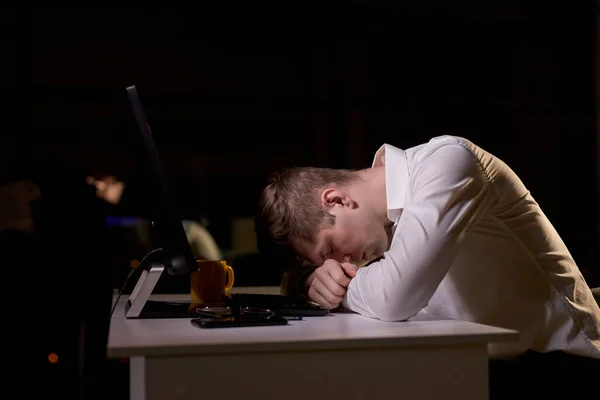 Νεαρός καυκάσιος άντρας κοιμάται στο γραφείο τη νύχτα, χρειάζεται περισσότερη ξεκούραση. — Φωτογραφία Αρχείου