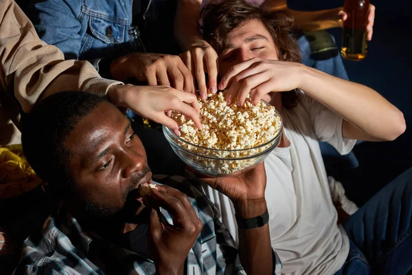 Többnemzetiségű fiatal barátok együtt néznek filmet este, harapnivalókat esznek — Stock Fotó
