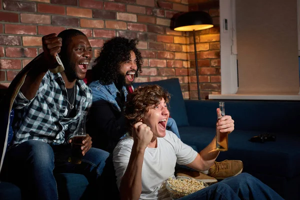 Los fanáticos de los deportes afroamericanos celebran la victoria en casa. Apasionados partidarios gritan viendo el partido en la televisión — Foto de Stock