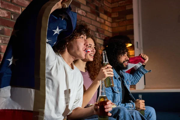 Američtí přátelé pijící pivo při povzbuzování oblíbeného týmu na fotbalovém mistrovství v televizi — Stock fotografie