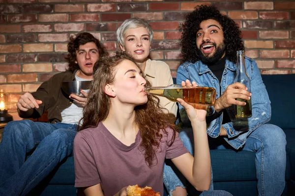 Jóvenes amigos viendo la televisión, programa de comedia o película, comer bocadillos y bebidas, sentado en el sofá acogedor en casa — Foto de Stock