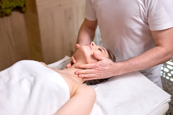 Zrelaksowana kobieta dostaje masaż twarzy w spa.Caucasian kobieta z zamkniętymi oczami relaks w spa — Zdjęcie stockowe