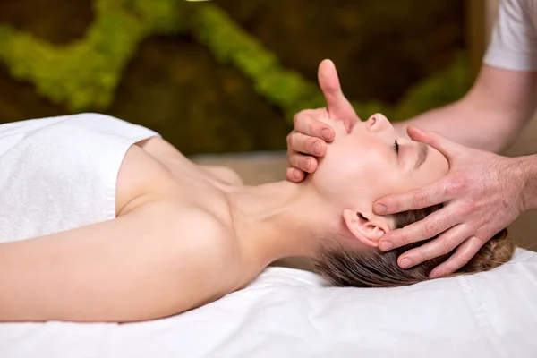 Jong mooi vrouw liggend op massage tafel en genieten van massage door professionele — Stockfoto