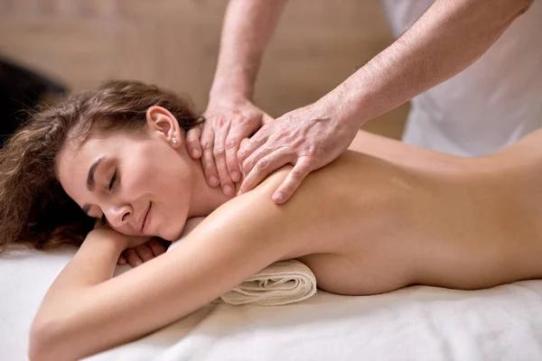 Calmo jovem caucasiano recebendo massagem de corpo inteiro no spa moderno, vista lateral — Fotografia de Stock