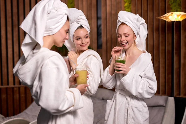 Atractivas mujeres disfrutan de beber bebidas saludables durante el tratamiento de spa en el salón de belleza — Foto de Stock