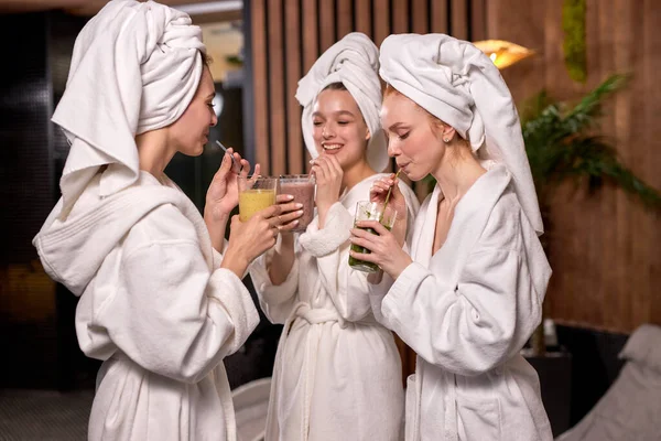 Tres novias guapas bebiendo jugosa bebida y charlando animadamente mientras se relaja en el salón de spa —  Fotos de Stock