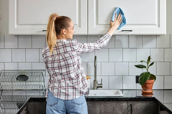 Vista trasera de la cocina de limpieza de mujer con detergente en aerosol y paño de cocina, concepto de higiene — Foto de Stock