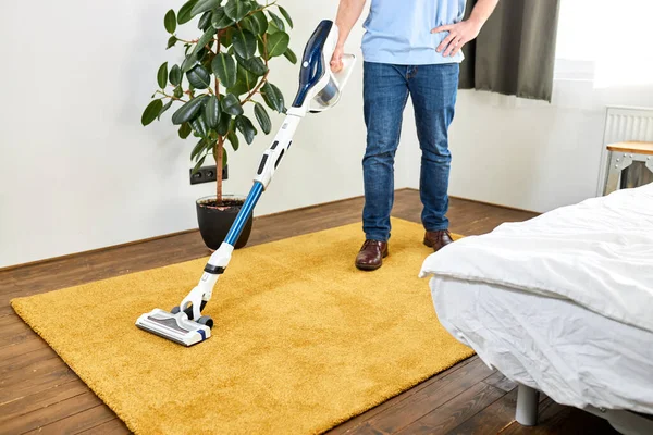 Lantai pembersih laki-laki dipotong dengan vacuum cleaner di ruang tamu putih modern — Stok Foto