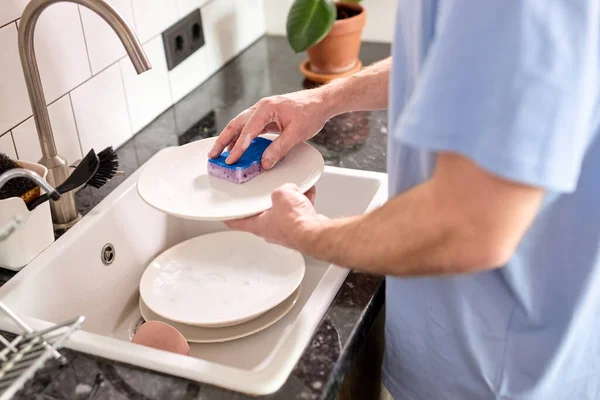 Manos masculinas irreconocibles lavando platos en el fregadero de la cocina mientras se hace la limpieza en casa los fines de semana —  Fotos de Stock