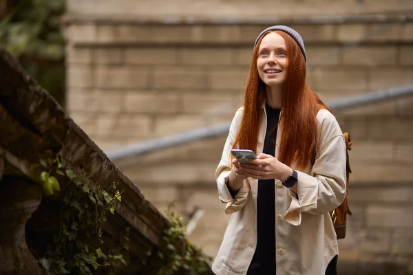 Lycklig kvinna promenader på historisk plats som håller smartphone, kommer att ta foto — Stockfoto