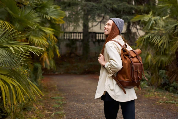 Sett bakifrån modern turist kvinna med ryggsäck med utflykt i trädgården — Stockfoto