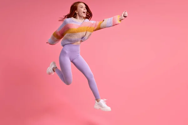 Entzückend süße lustige Frau springt im Studio auf und hebt die Hände nach vorne — Stockfoto