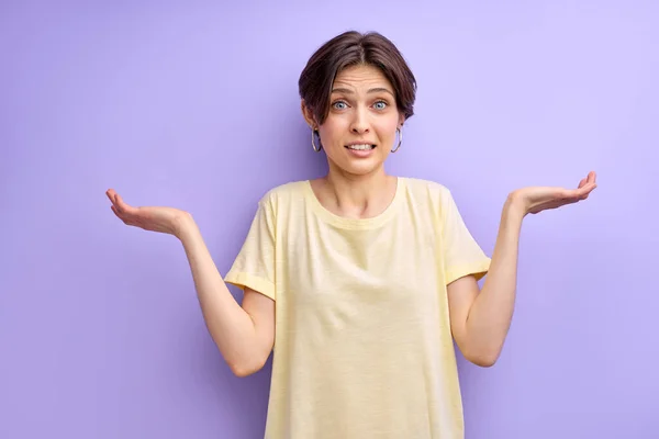 Молода жінка з відкритими руками просить вибачення, ізольована на фіолетовому — стокове фото