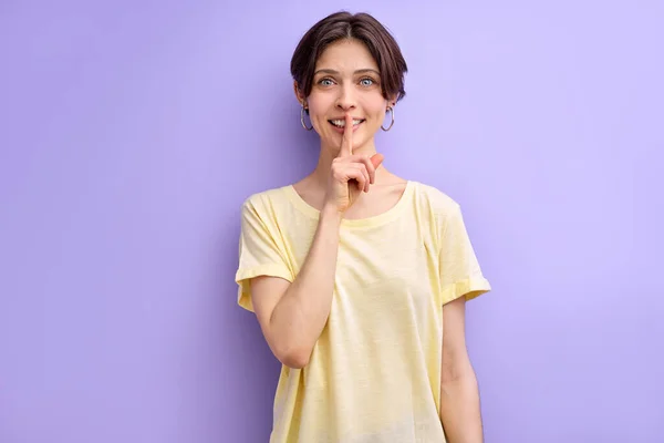 Smiling woman asking for silence and quiet, gesturing with finger in front of mouth, saying shh — Stock fotografie