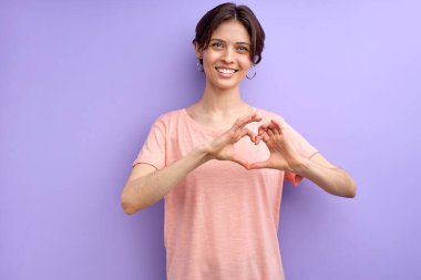 Tatlı, beyaz, yetişkin bir kadın. Sevgi ve dostluk ifade ediyor. Ellerden kalp şekli alıyor.