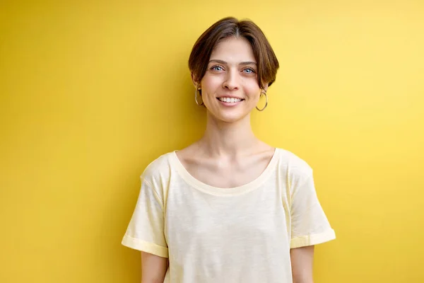 Портрет взрослой женщины, мило улыбающейся, позирующей перед камерой, изолированной на желтом фоне — стоковое фото