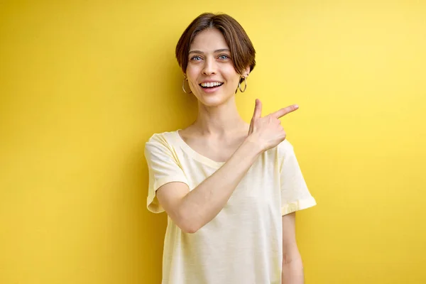 Αρκετά όμορφη θετική ενήλικη γυναίκα δείχνει το δάχτυλο στο πλαϊνό αντίγραφο χώρο για διαφήμιση — Φωτογραφία Αρχείου