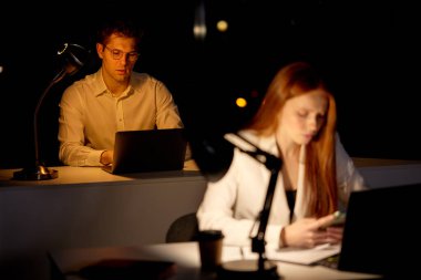 Ofiste geç saatlere kadar çalışan ciddi bir konsantre yönetici. Ofis karanlık.