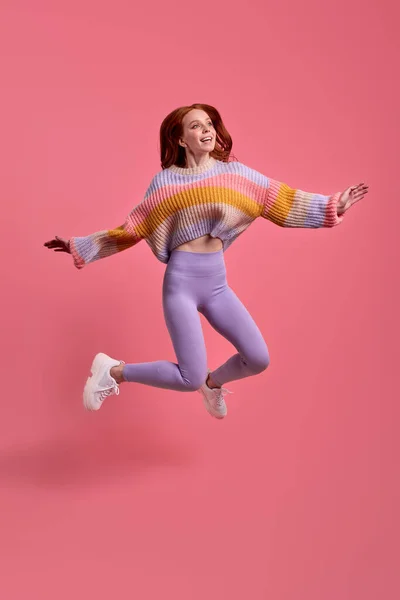 Забавная очаровательная юная леди в повседневной одежде, прыгающая с распростертыми объятьями — стоковое фото