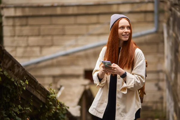 Söt glad kvinna promenader i staden och använda smartphone, surfa på Internet — Stockfoto