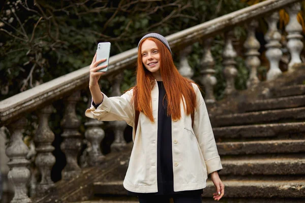 Porträtt av söt modern kvinna tar selfie, Foto på bakgrunden av byggnaden — Stockfoto