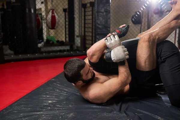 Grappler försöker kväva motståndaren i markstrid, träning på gym — Stockfoto