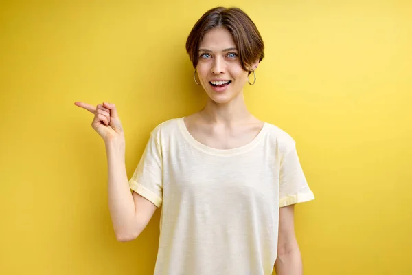 Довольно симпатичная позитивная взрослая женщина, указывающая пальцем на место для рекламы — стоковое фото