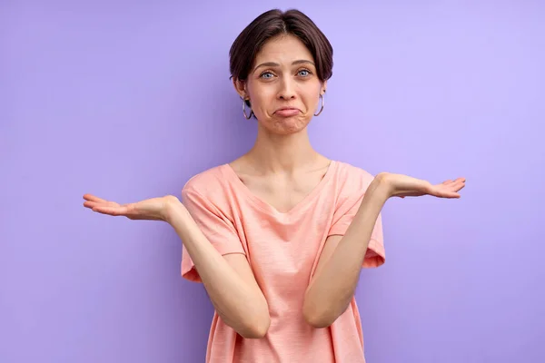 Dissatisfied woman spreads arms, its a pity. isolated on purple background — Stock Photo, Image