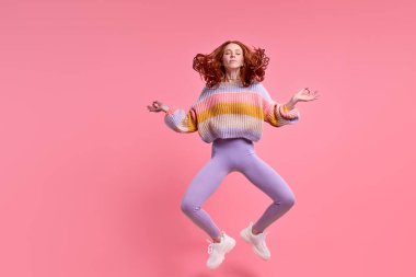 Çekici kızıl saçlı kadın yüksek atlayan Lotus pozunda sabah yogası yapıyor.