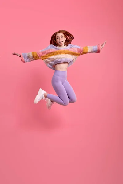 Захватывающая очаровательная юная леди, одетая в повседневную одежду, прыгающая с распростертыми объятьями — стоковое фото