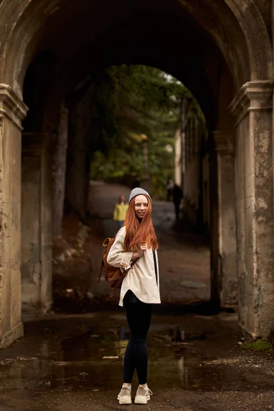 Bakifrån på resenär kvinna med ryggsäck stå i historiska antika båge, utforska — Stockfoto