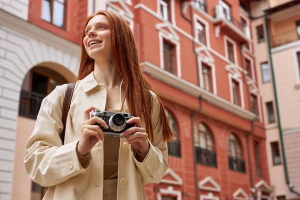 Vit rödhårig kvinna turist i rock står på gatan i gamla stan och skytte på kameran — Stockfoto