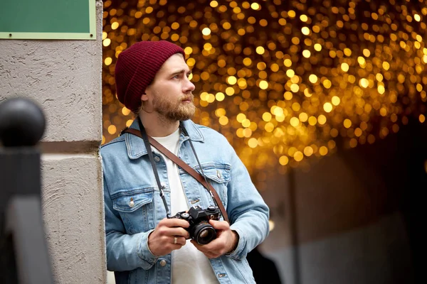 Caucasian hipster guy in denim jacket walk in city street taking photo, using film camera