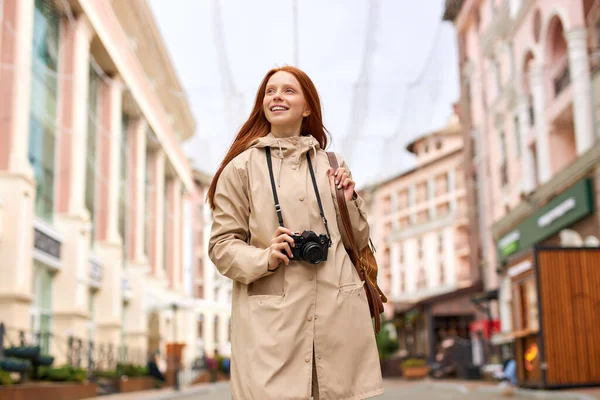 Ung leende kvinna turist promenader runt staden på våren, håller retrokamera — Stockfoto