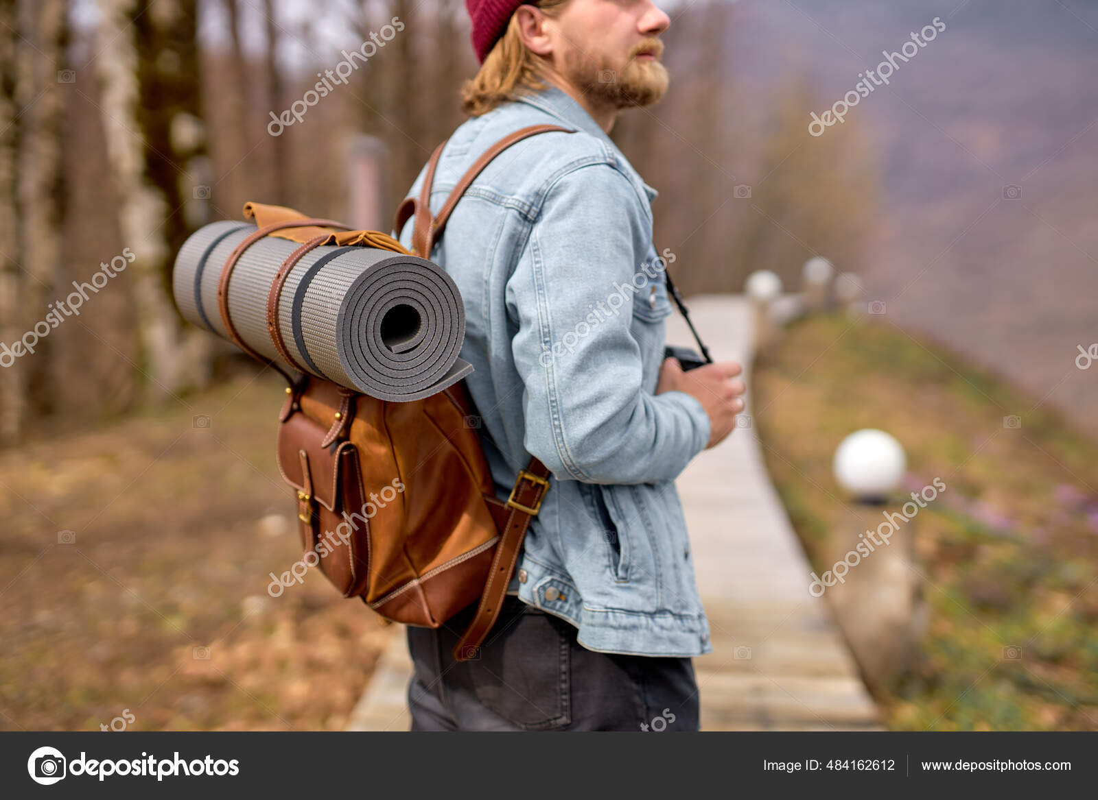 Hipster man with backpack exploring nature in spring, walking